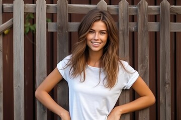 Wall Mural - Blank white t-shirt, beautiful woman model wearing t-shirt at wooden fence background