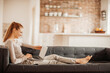 © Geber86 - Young woman using her laptop on the couch at home