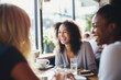 © Jasmina - Happy smiling female friends sitting in a café laughing and talking during a lunch break