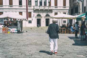 Wall Mural - Unidentified senior tourist or local walking on the cobblestone alleys in Venice, Italy. Vintage picture.