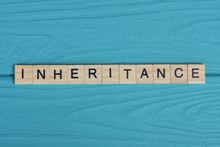 Word Inheritance Made From Wooden Gray Letters Lies On A Blue Background