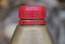 One Brown Plastic Canister With A Red Lid On The Street On A Gray Background