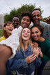 Vertical photo of Cheerful group of friends taking smiling selfie. Group of young people having fun together outdoors at park in the city enjoying travel in vacation holidays. High quality photo