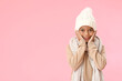 Cute African-American boy in warm winter clothes on pink background