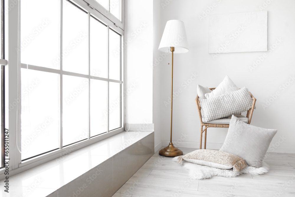 Armchair with pillows and lamp in light room