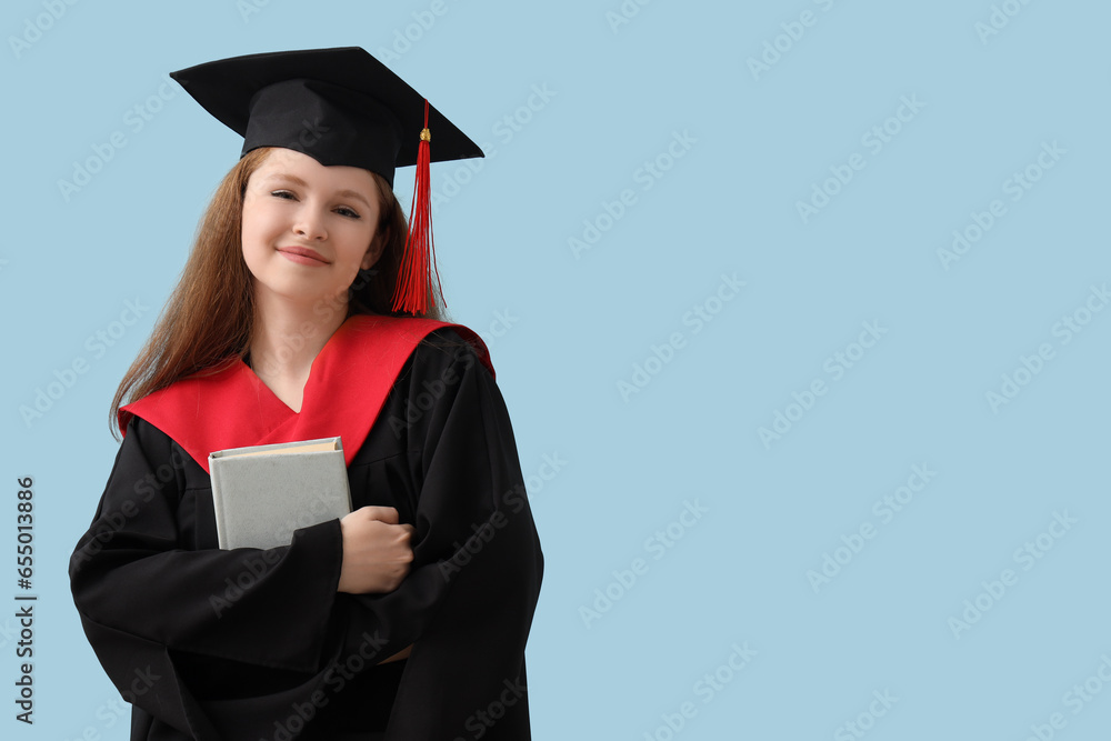 Female graduate student with book on blue background