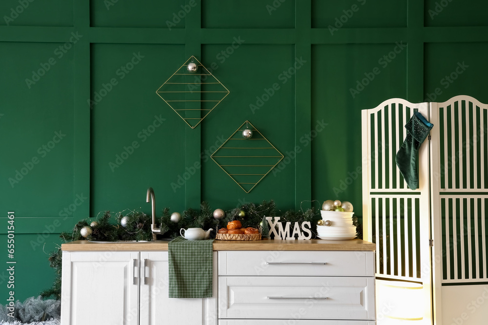 White kitchen counter with Christmas decor near green wall