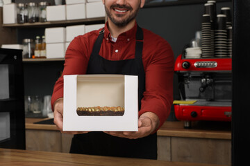 Wall Mural - Business owner in his cafe. Man holding box with cake at desk, selective focus