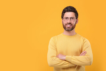 Poster - Portrait of handsome man in glasses on orange background, space for text