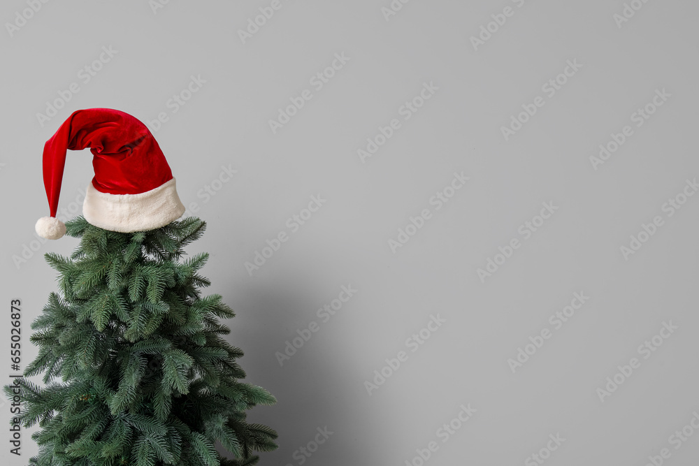 Christmas tree with Santa hat near white wall
