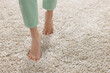 © New Africa - Woman walking on soft light brown carpet at home, closeup. Space for text