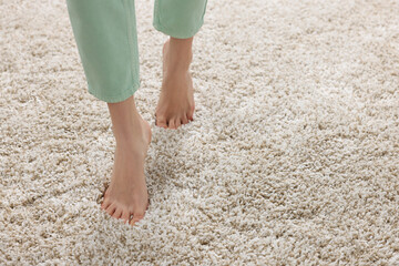 Poster - Woman walking on soft light brown carpet at home, closeup. Space for text