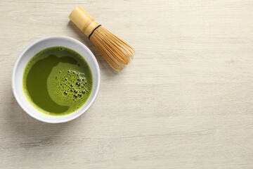 Wall Mural - Cup of fresh matcha tea and bamboo whisk on white wooden table, flat lay. Space for text