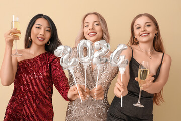 Canvas Print - Young women with champagne and figure 2024 celebrating Christmas on beige background