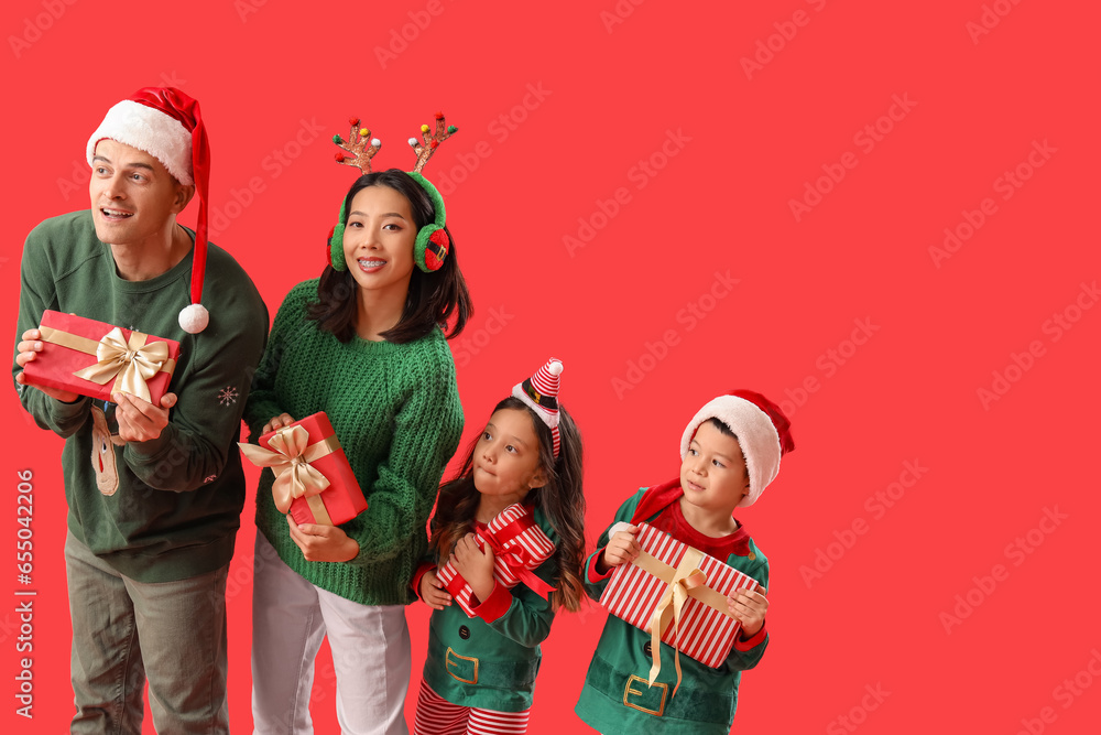 Happy family with Christmas presents on red background