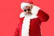 © Pixel-Shot - Cool Santa Claus in sunglasses on red background