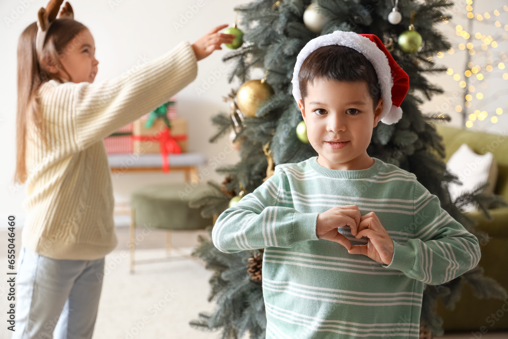Cute little boy making heart gesture at home on Christmas eve
