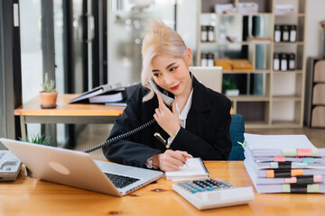 Happy asian business woman have the joy of talking on the smartphone, tablet and laptopon the modern office