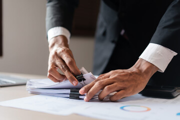 Wall Mural - Businessman stacking business document after examining marketing data of startup business project