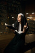 Nun woman reading bible, smoking cigarette and showing obscene hand gesture