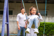 © Art_Photo - Portrait of enjoy happy love asian family father and mother with little asian girl smiling playing and pushing daughter on the swing moments good time at playground