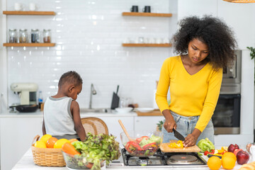 Wall Mural - Portrait of enjoy happy love african american family mother and african little boy son child having fun help cooking food healthy eat together with fresh vegetable salad and ingredient in kitchen