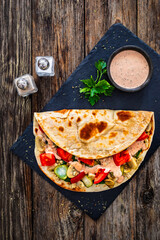 Poster - Italian piada wraps - piadina filled with mozzarella cheese, fried pork and vegetables and on wooden table
