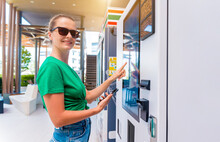 Young Woman Paying For Coffee At Vending Machine Using Contactless Method Of Payment 