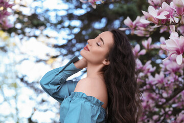 Wall Mural - Beautiful woman near blossoming magnolia tree on spring day