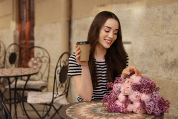 Wall Mural - Beautiful woman with bouquet of spring flowers and coffee in outdoor cafe, space for text