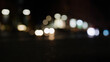 Low angle bokeh background of night city with car light passing by