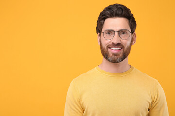 Wall Mural - Portrait of handsome man in glasses on orange background, space for text