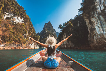 Wall Mural - Traveler asian woman relax and travel on Thai longtail boat in Ratchaprapha Dam at Khao Sok National Park Surat Thani Thailand