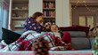 young single mother apprehensive combs her daughter on the sofa at home during winter vacation, family moments and love