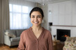 © fizkes - Head shot portrait positive Indian woman standing in modern living room at home, happy beautiful young female with healthy toothy smile and perfect skin looking at camera, posing for profile picture