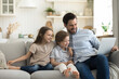 © fizkes - Happy handsome young father sits on sofa enjoy weekend time with cute little 6s children, hold laptop watch funny video, online TV family channel, doing e-shopping, laugh feels happy, use modern tech