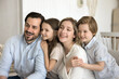 © fizkes - Friendly dreamy couple and children looking away rest on sofa at new apartment, parents enjoy spend time together with two little kids, have fun, show love and care. Family portrait of two generation