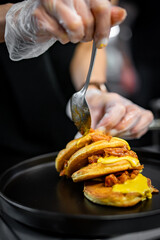 Poster - woman chef hand cooking pancakes with meat, bacon and cheese sauce