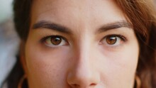 Extreme Close-up Macro Portrait Of Smiling Young Adult Caucasian Woman Face. Brunette Girl Eyes, Looking At Camera. Dark Brown Eyes Of Lady. Portrait Of Positive Female Opening Wide Her Closed Eyes