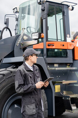 Sticker - Serviceman with digital tablet on a background of the tractor.