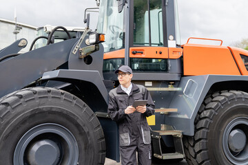 Sticker - Serviceman with digital tablet on a background of the tractor.