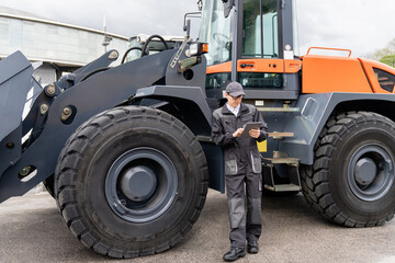Poster - Serviceman with digital tablet on a background of the tractor.