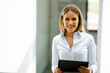 © BGStock72 - Young woman with digital tablet standing in the modern office hallway