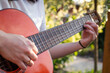 A girl plays an acoustic guitar in the garden. Close-up of female hands playing a classical guitar.
