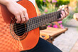 A girl plays an acoustic guitar in the garden. Close-up of female hands playing a classical guitar.
