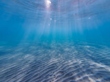 Fototapeta Łazienka - Sandy bottom on the beach in Greece, the sun's rays break through the water.  Underwater photo.