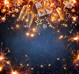 Wall Mural - new year celebration - lights with champagne glasses and gift boxes with golden ornaments on blue ba