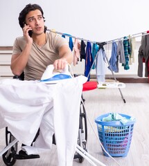 Sticker - Young man in wheel-chair doing ironing at home