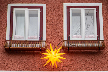 Christmas decoration - a shining star hangs between the windows of the house