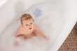 © New Africa - Cute little baby bathing in tub at home, top view